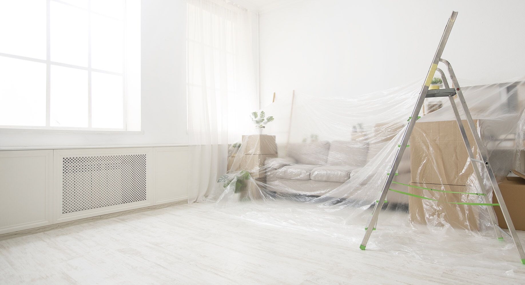 Sofa and boxes covered by transparent dust sheets